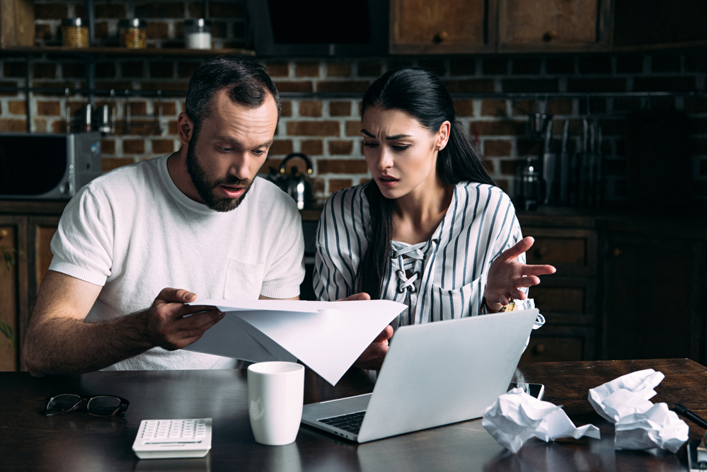 Shocked couple looking at paperwork in front of computer