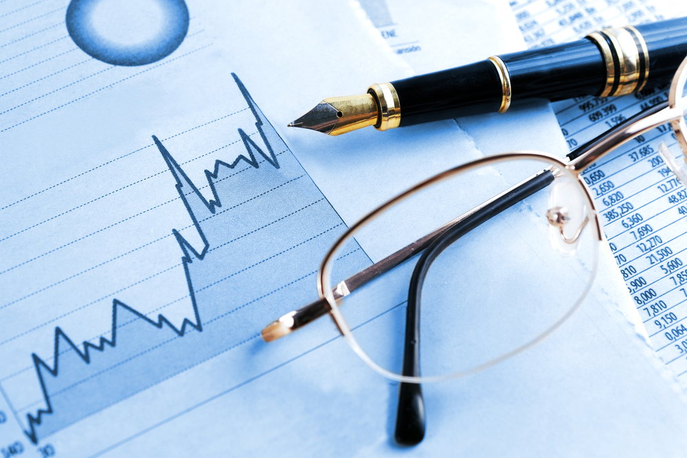 Business financials and graph with pen and glasses